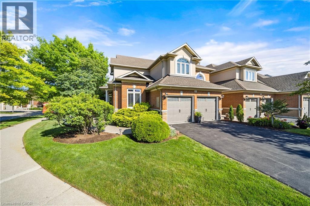 View of front facade featuring brick siding, asphalt driveway, a garage, a front lawn, and stucco siding - 4165 Stonebridge Crescent, Burlington, ON - Outdoor With Facade