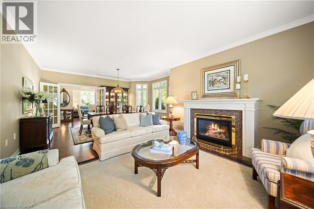 Living area with ornamental molding, a fireplace, a chandelier, and wood finished floors - 4165 Stonebridge Crescent, Burlington, ON - Indoor Photo Showing Living Room With Fireplace