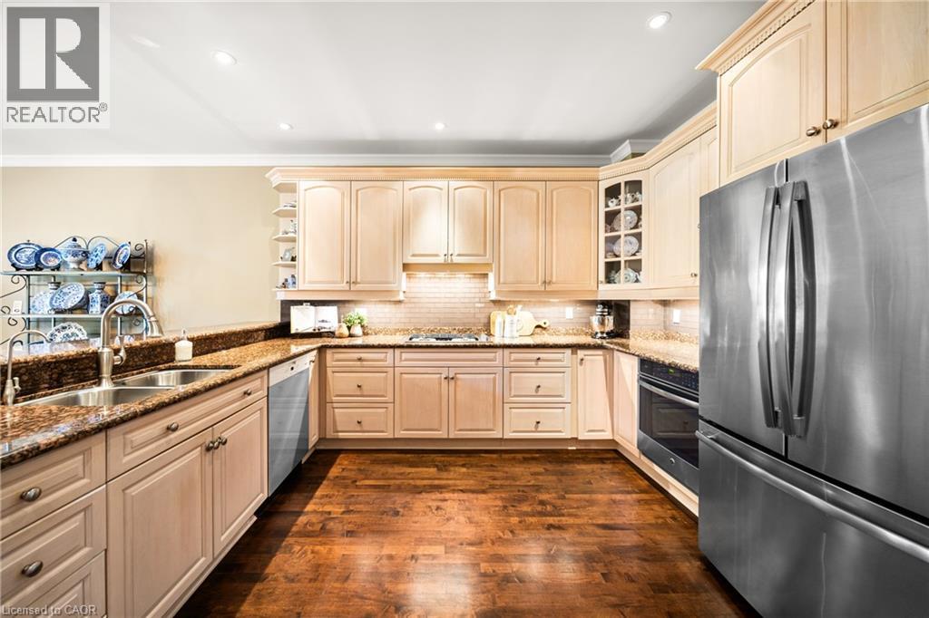Kitchen with stainless steel appliances, light stone countertops, dark wood-style flooring, glass insert cabinets, and recessed lighting - 4165 Stonebridge Crescent, Burlington, ON - Indoor Photo Showing Kitchen With Double Sink