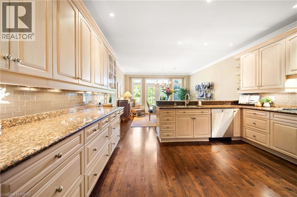 Kitchen with tasteful backsplash, dark stone countertops, a chandelier, a peninsula, and dishwasher - 4165 Stonebridge Crescent, Burlington, ON - Indoor Photo Showing Kitchen With Upgraded Kitchen