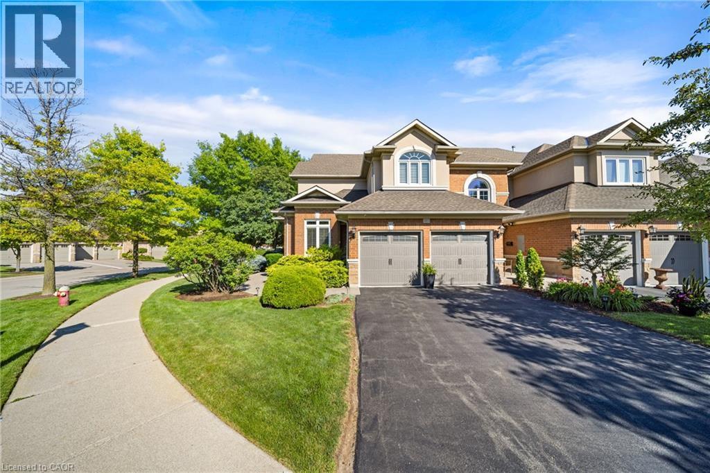 View of front of house featuring asphalt driveway, brick siding, a front lawn, a garage, and a shingled roof - 4165 Stonebridge Crescent, Burlington, ON - Outdoor With Facade