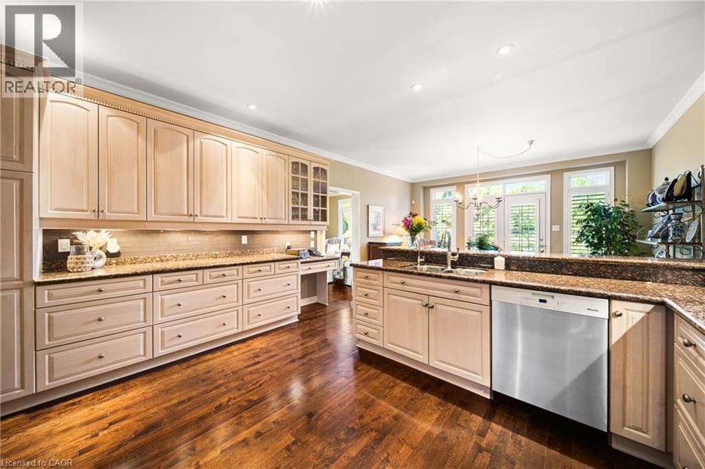 Kitchen with dishwasher, glass insert cabinets, dark stone countertops, dark wood-type flooring, and crown molding - 4165 Stonebridge Crescent, Burlington, ON - Indoor Photo Showing Kitchen