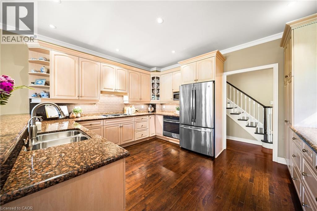 Kitchen with stainless steel appliances, ornamental molding, open shelves, tasteful backsplash, and glass insert cabinets - 4165 Stonebridge Crescent, Burlington, ON - Indoor Photo Showing Kitchen With Double Sink