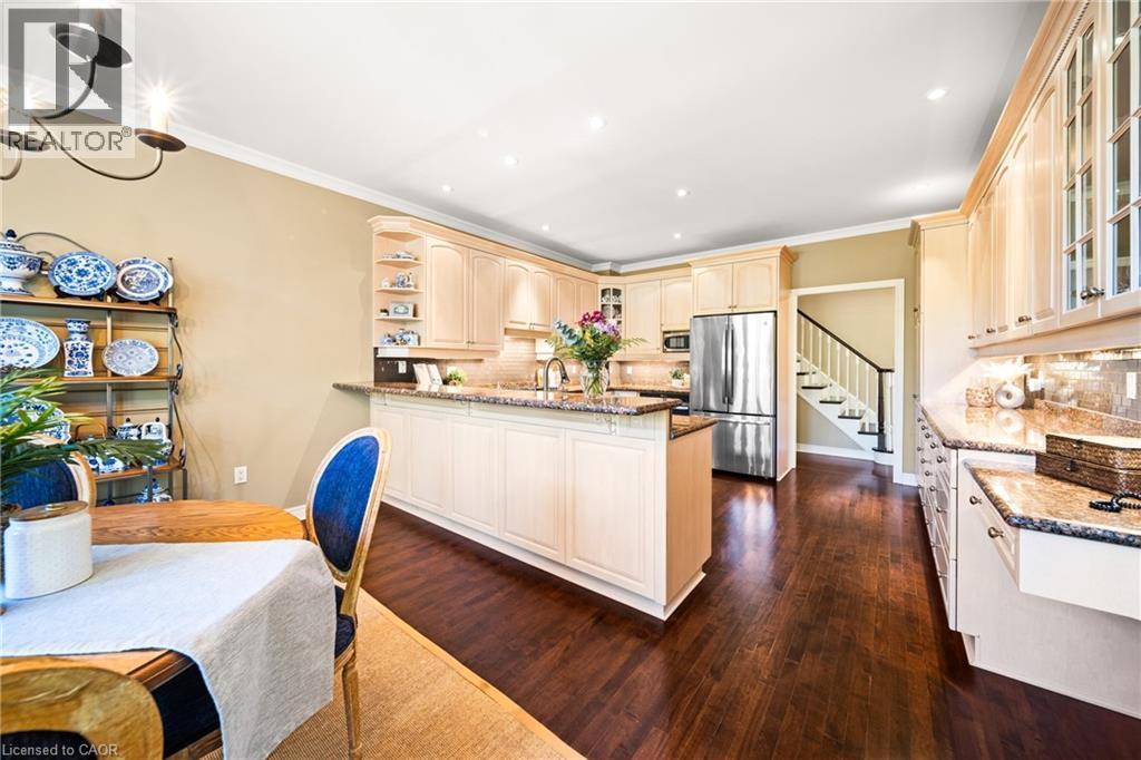 Kitchen featuring glass insert cabinets, backsplash, dark stone counters, appliances with stainless steel finishes, and recessed lighting - 4165 Stonebridge Crescent, Burlington, ON - Indoor Photo Showing Kitchen With Upgraded Kitchen