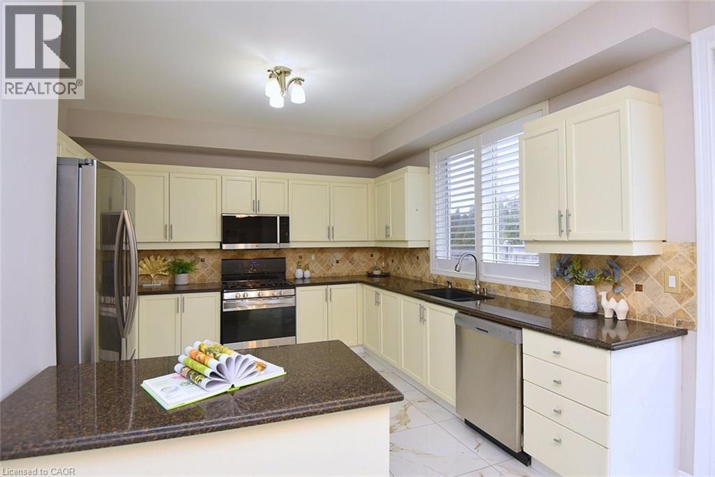 Kitchen featuring appliances with stainless steel finishes, dark stone countertops, light marble finish floors, and tasteful backsplash - 5109 Blue Spruce Avenue, Burlington, ON - Indoor Photo Showing Kitchen