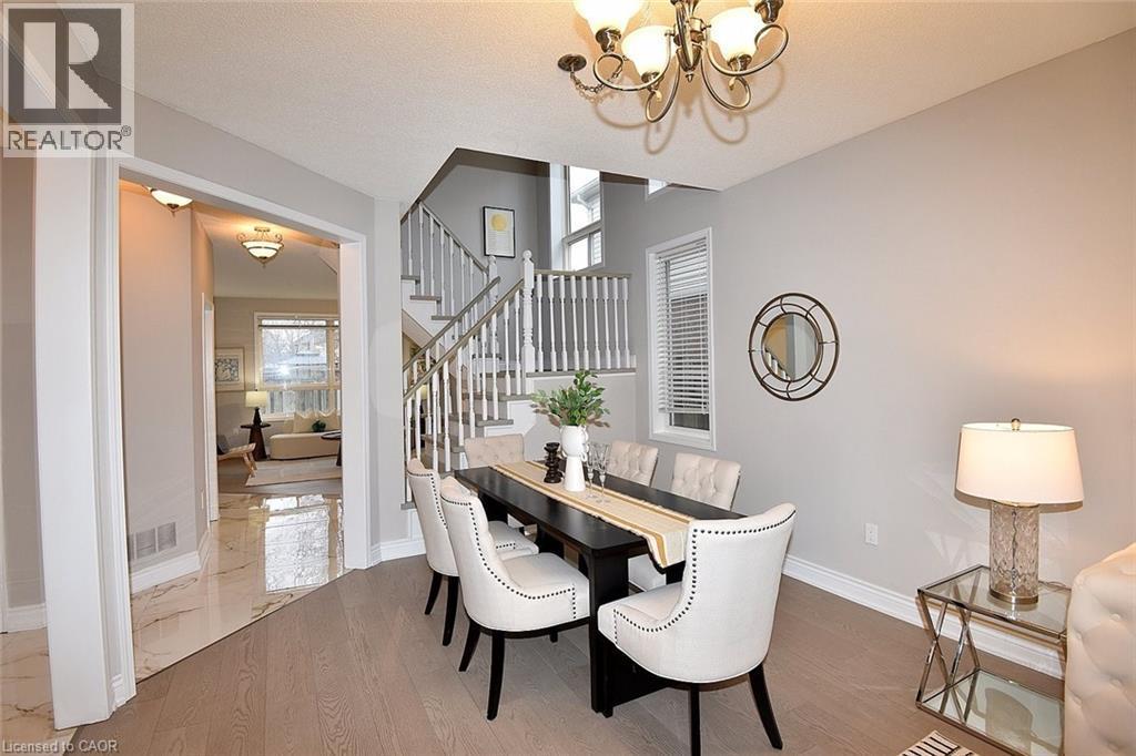 Dining room with a chandelier, wood finished floors, stairway, and a textured ceiling - 5109 Blue Spruce Avenue, Burlington, ON - Indoor Photo Showing Dining Room