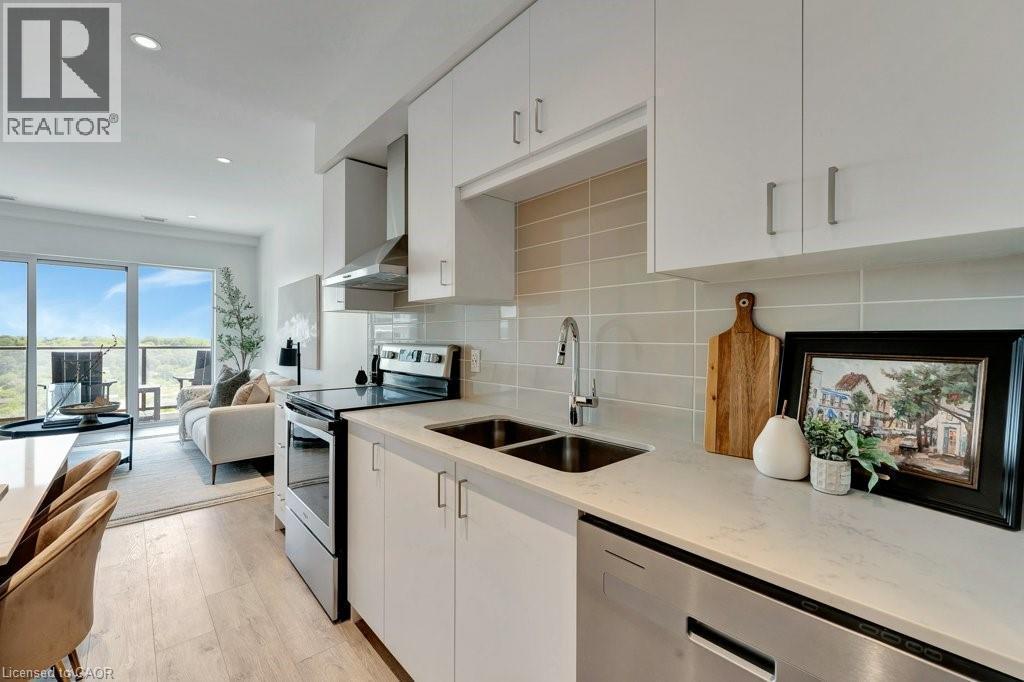 Kitchen featuring appliances with stainless steel finishes, wall chimney exhaust hood, decorative backsplash, light stone counters, and white cabinets - 15 Glebe Street Unit# 1511, Cambridge, ON - Indoor Photo Showing Kitchen With Double Sink With Upgraded Kitchen
