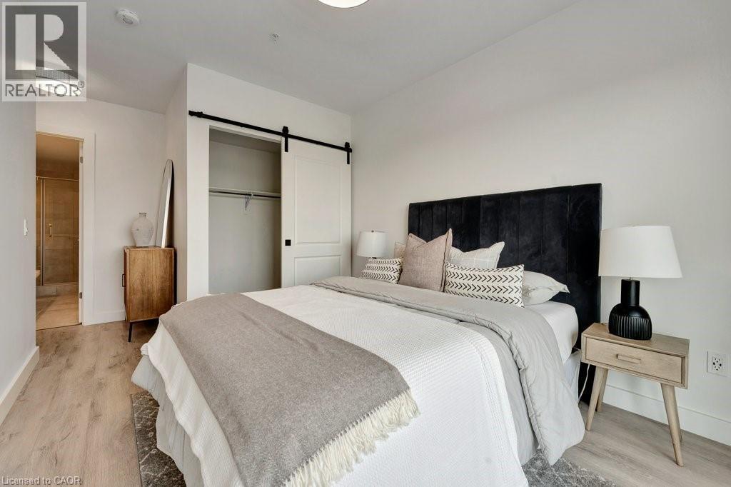 Bedroom featuring a barn door, light wood-style floors, and a closet - 15 Glebe Street Unit# 1511, Cambridge, ON - Indoor Photo Showing Bedroom