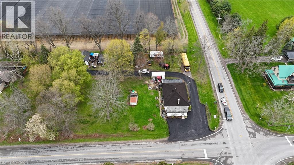 Aerial property overview featuring a dark shingle roof, paved driveway, and mature landscaping - 740 Hillcrest Road, Simcoe, ON - Outdoor With View