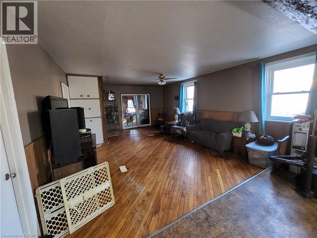 Living room with wainscoting, wood walls, a textured ceiling, wood-type flooring, and a ceiling fan - 740 Hillcrest Road, Simcoe, ON - Indoor