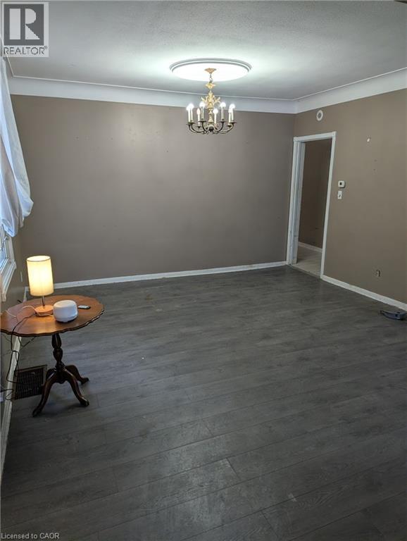 Unfurnished dining area featuring ornamental molding, dark wood-style flooring, a textured ceiling, and a chandelier - 151 Gibson Avenue, Hamilton, ON - Indoor Photo Showing Other Room