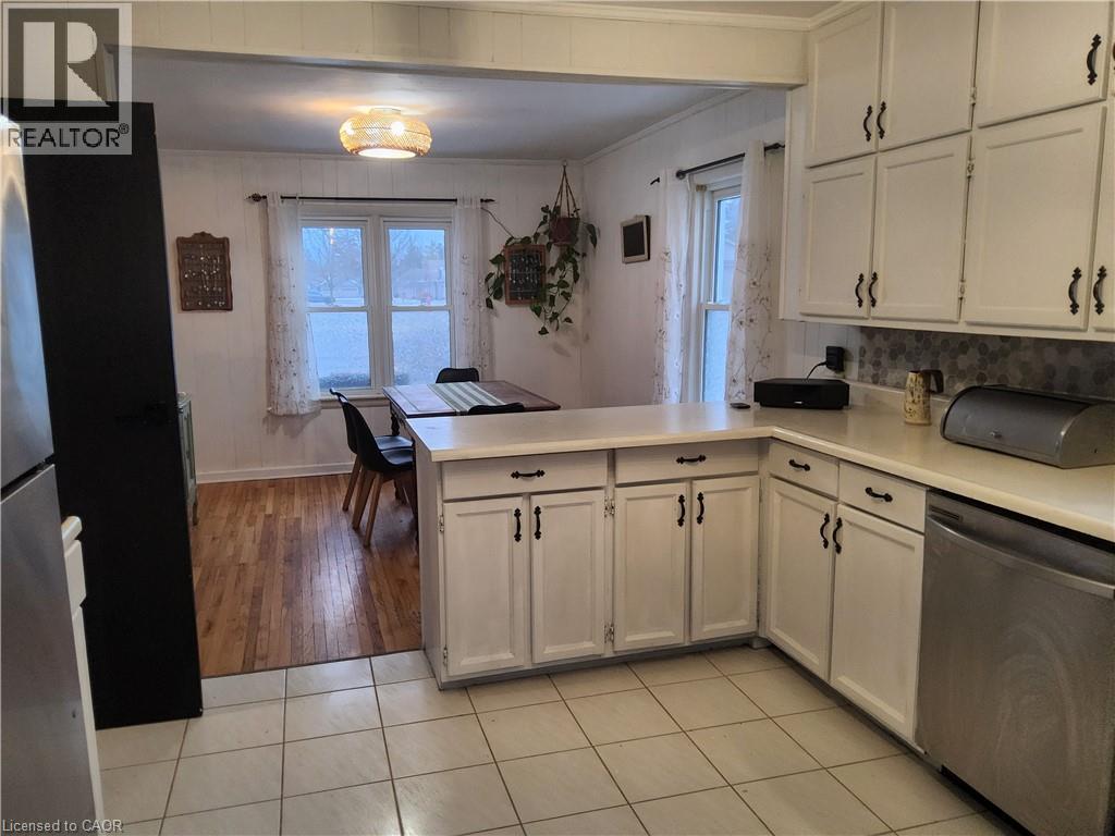 Kitchen with appliances with stainless steel finishes, a peninsula, light countertops, ornamental molding, and plenty of natural light - 509 Queensway W, Simcoe, ON - Indoor Photo Showing Kitchen