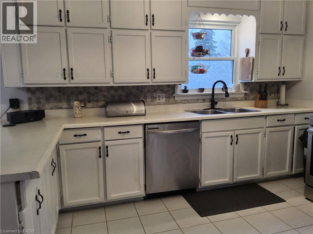 Kitchen with dishwasher, light countertops, white cabinets, and decorative backsplash - 509 Queensway W, Simcoe, ON - Indoor Photo Showing Kitchen With Double Sink