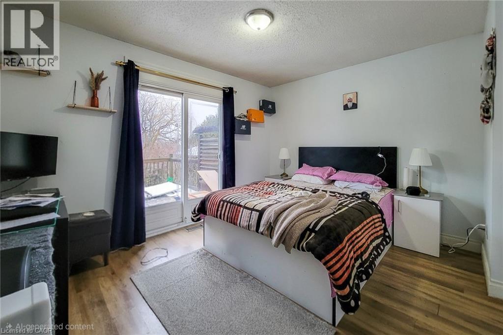 Bedroom featuring access to exterior, a textured ceiling, and wood finished floors - 758 Stone Church Road E, Hamilton, ON - Indoor Photo Showing Bedroom