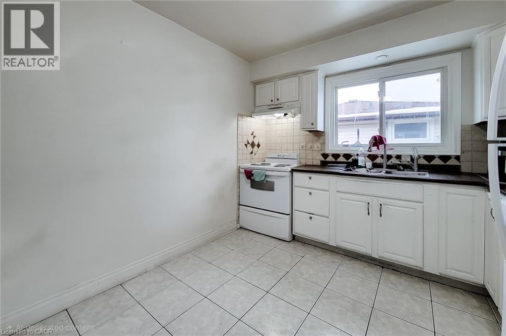 Kitchen with dark countertops, electric range, white cabinetry, under cabinet range hood, and backsplash - 758 Stone Church Road E, Hamilton, ON - Indoor Photo Showing Kitchen With Double Sink