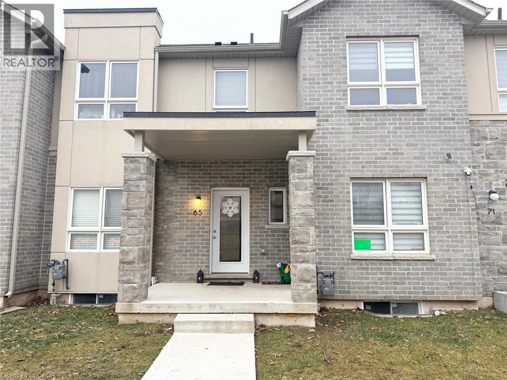 View of front facade with a porch, brick siding, and a front yard - 65 Old School Trail Unit# 36, Welland, ON - Outdoor