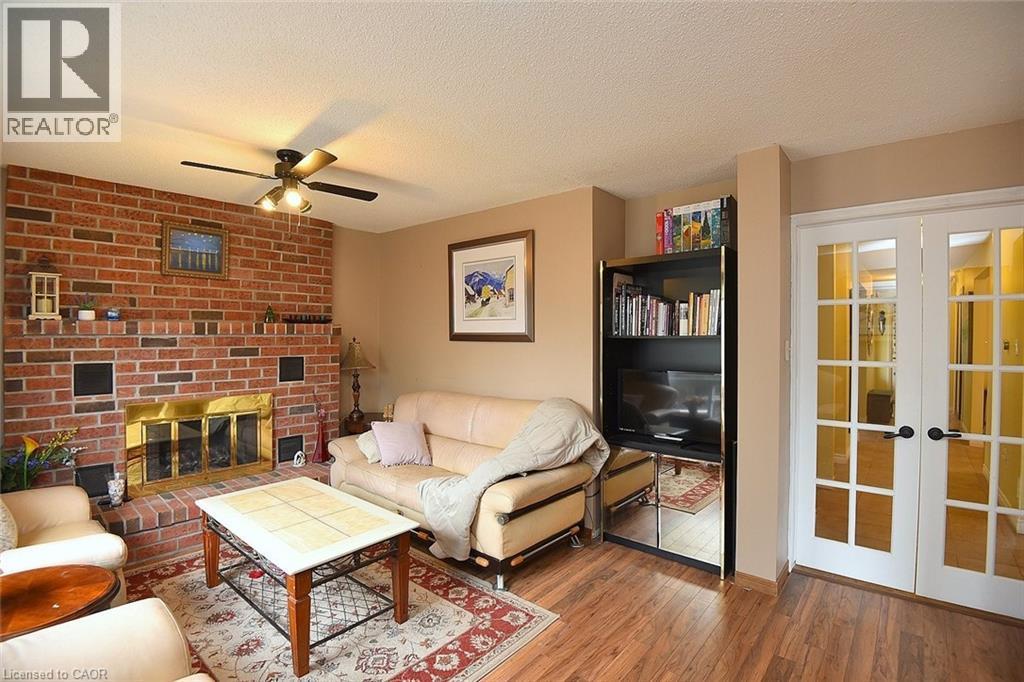 Living room featuring french doors, a textured ceiling, wood finished floors, a ceiling fan, and a fireplace - 43 Niska Drive, Waterdown, ON - Indoor Photo Showing Living Room With Fireplace