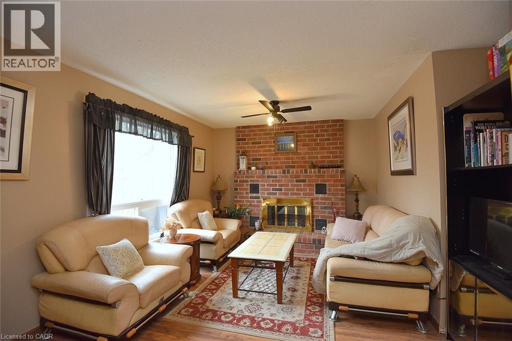 Living area with a fireplace, a textured ceiling, wood finished floors, and ceiling fan - 43 Niska Drive, Waterdown, ON - Indoor Photo Showing Living Room With Fireplace