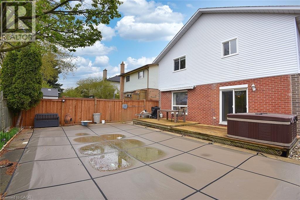 Back of property with a wooden deck, a fenced backyard, brick siding, a hot tub, and a patio - 43 Niska Drive, Waterdown, ON - Outdoor With Exterior