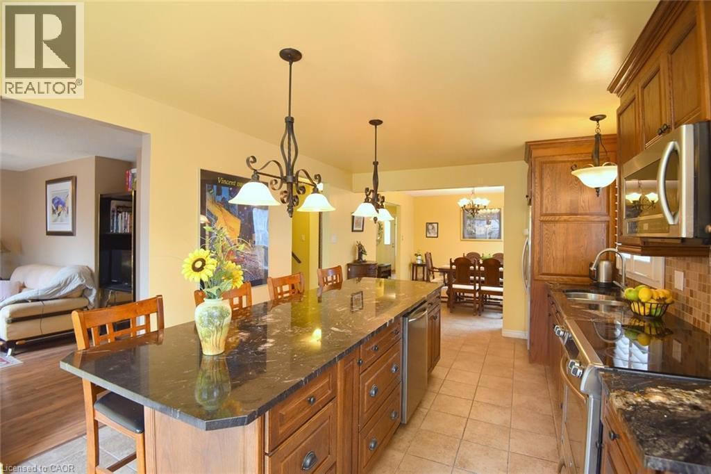 Kitchen featuring a kitchen breakfast bar, brown cabinets, stainless steel appliances, and dark stone counters - 43 Niska Drive, Waterdown, ON - Indoor Photo Showing Kitchen With Double Sink With Upgraded Kitchen