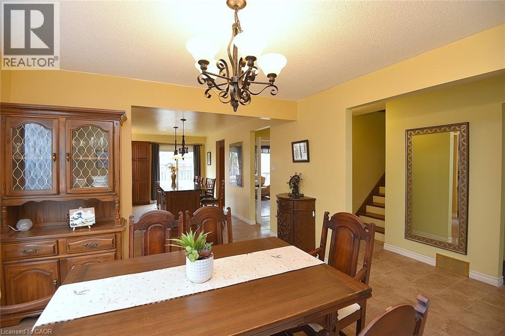 Dining area with a chandelier, stairs, a textured ceiling, and light tile patterned floors - 43 Niska Drive, Waterdown, ON - Indoor Photo Showing Dining Room