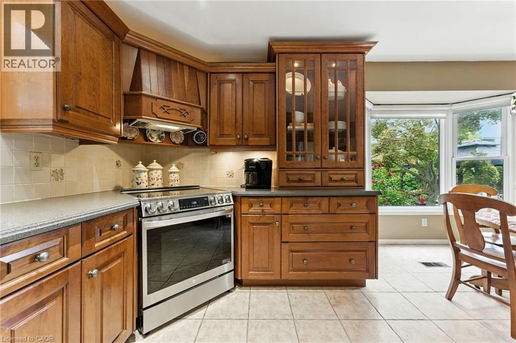 Kitchen featuring stainless steel electric range, light tile patterned flooring, backsplash, custom exhaust hood, custom maple cabinetry - 3 Atkins Drive, Hamilton, ON - Indoor Photo Showing Kitchen