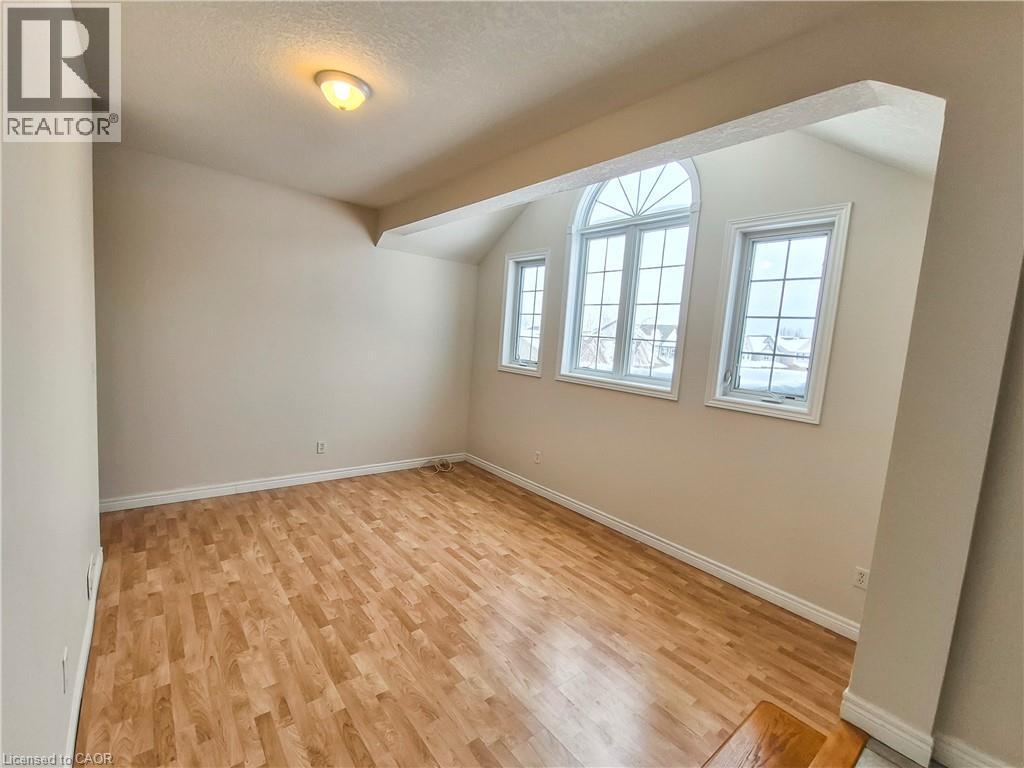 Spare room featuring light wood-style flooring, a textured ceiling, and vaulted ceiling - 132 Udvari Crescent Unit# 3, Kitchener, ON - Indoor Photo Showing Other Room