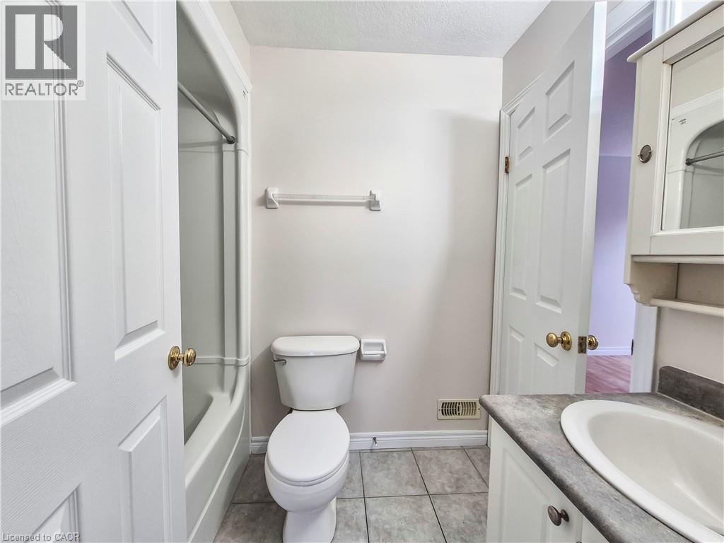 Bathroom with vanity, bathtub / shower combination, a textured ceiling, and light tile patterned floors - 132 Udvari Crescent Unit# 3, Kitchener, ON - Indoor Photo Showing Bathroom