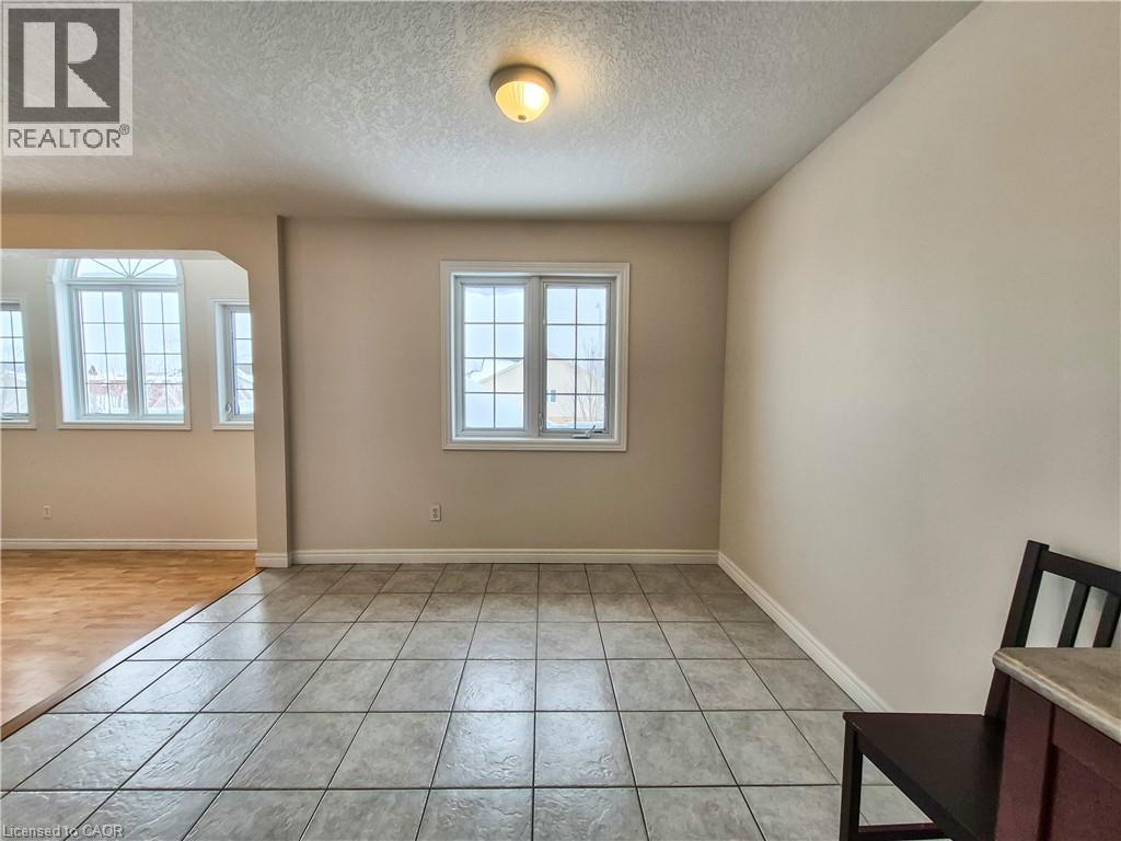 Unfurnished room featuring a textured ceiling, arched walkways, and light tile patterned flooring - 132 Udvari Crescent Unit# 3, Kitchener, ON - Indoor Photo Showing Other Room