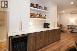 Bar featuring open shelves, wine cooler, white cabinets, light wood finished floors, and recessed lighting -