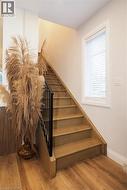 Stairs with wood finished floors and healthy amount of natural light -