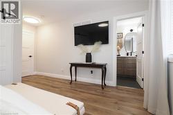Bedroom with a barn door, dark wood-style flooring, and connected bathroom -