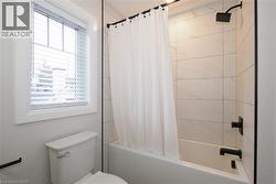 Full bath featuring shower / bath combo with shower curtain and toilet -