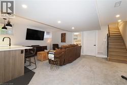 Living room featuring stairs, light colored carpet, and recessed lighting -
