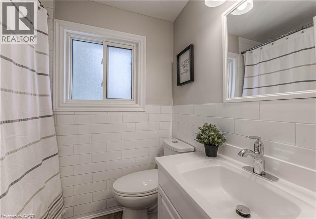 Bathroom featuring vanity, tile walls, a shower with shower curtain, and wainscoting - 156 Donald Street, Kitchener, ON - Indoor Photo Showing Bathroom