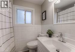 Bathroom featuring vanity, tile walls, a shower with shower curtain, and wainscoting -