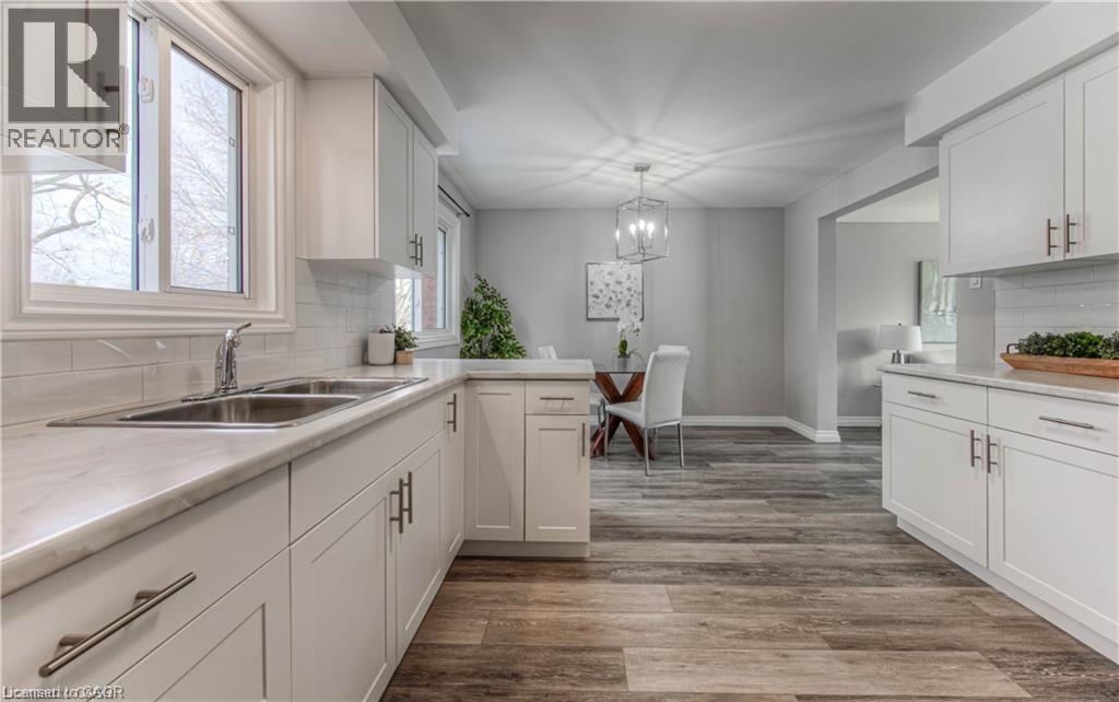 Kitchen with backsplash, white cabinetry, light countertops, and light wood-type flooring - 156 Donald Street, Kitchener, ON - Indoor Photo Showing Kitchen With Double Sink