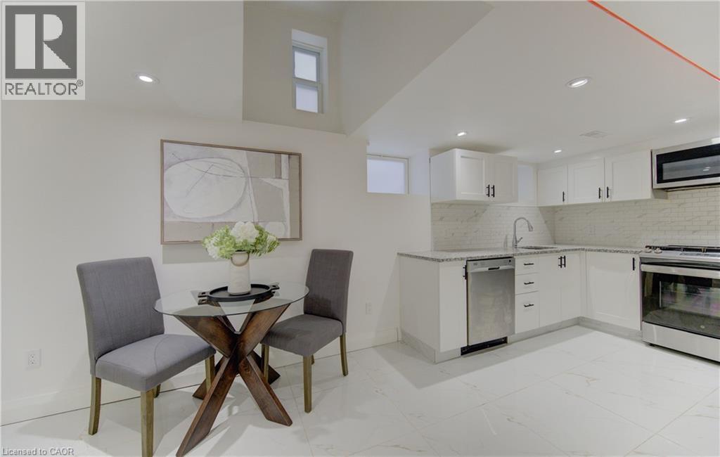 Kitchen featuring stainless steel appliances, light stone countertops, white cabinets, light marble finish flooring, and decorative backsplash - 569 Stirling Avenue S, Kitchener, ON - Indoor Photo Showing Kitchen