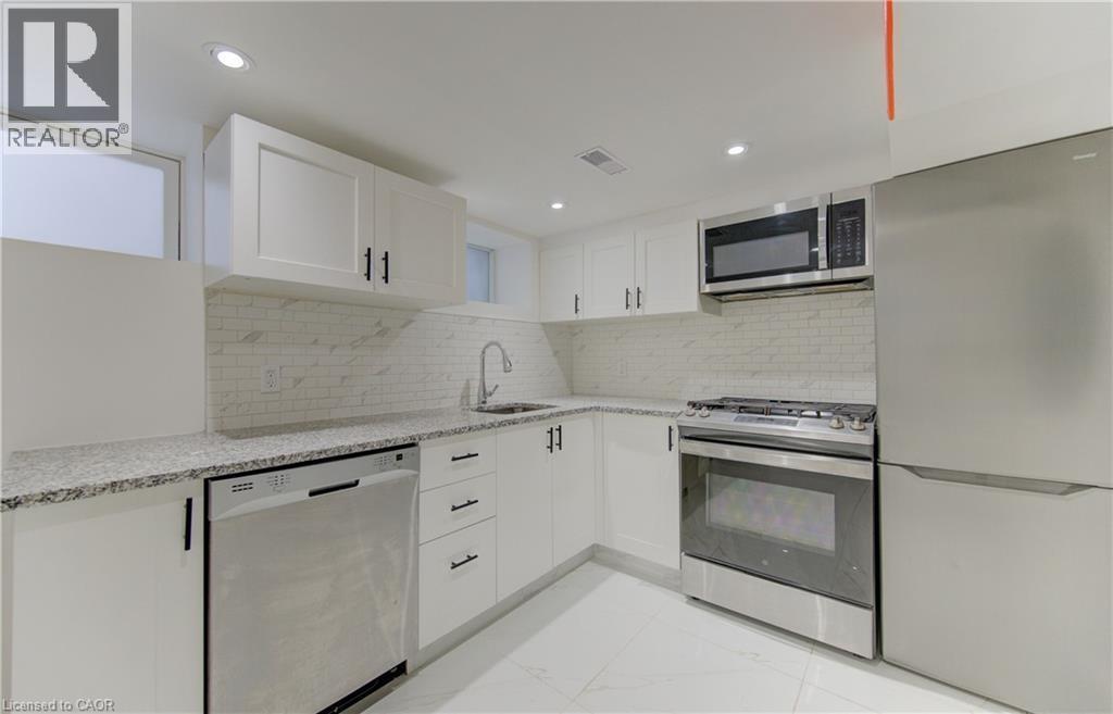 Kitchen featuring stainless steel appliances, white cabinets, light stone counters, decorative backsplash, and light marble finish flooring - 569 Stirling Avenue S, Kitchener, ON - Indoor Photo Showing Kitchen