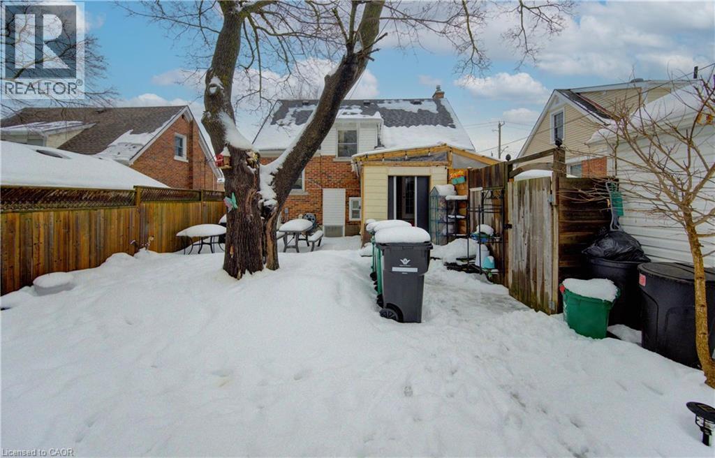 Snow covered house featuring a fenced backyard, brick siding, and an outbuilding - 569 Stirling Avenue S, Kitchener, ON - Outdoor