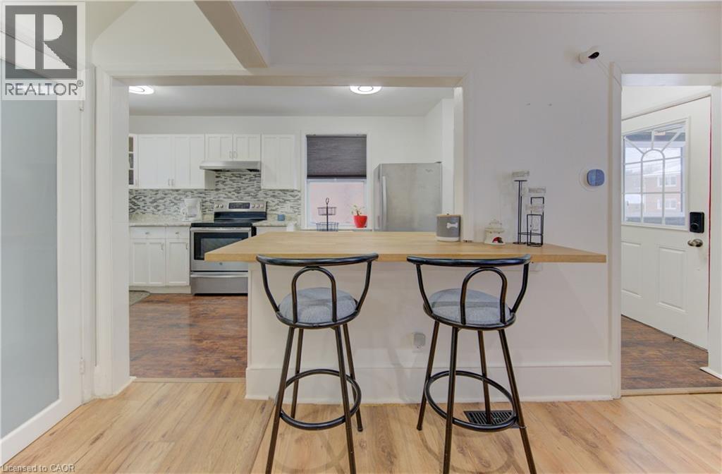 Kitchen featuring a kitchen bar, white cabinetry, electric stove, a peninsula, and freestanding refrigerator - 569 Stirling Avenue S, Kitchener, ON - Indoor Photo Showing Other Room