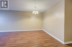 Empty room with wood finished floors and a chandelier -