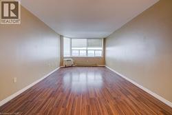 Unfurnished room with dark wood finished floors and baseboard heating -