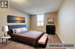 Bedroom with a textured ceiling, wood finished floors, and a baseboard radiator -
