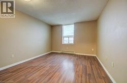 Empty room with a textured ceiling, wood finished floors, and a baseboard heating unit -
