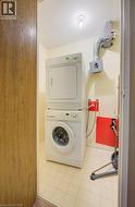 Laundry area featuring light floors and stacked washing machine and dryer -