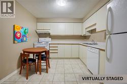 Kitchen with white appliances, light countertops, a textured ceiling, under cabinet range hood, and light tile patterned floors -