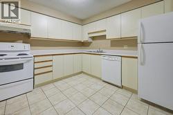 Kitchen featuring white appliances, a textured ceiling, light countertops, exhaust hood, and white cabinets -