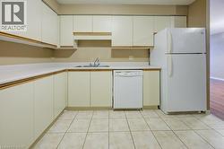Kitchen with light countertops, white appliances, white cabinetry, light tile patterned flooring, and a textured ceiling -