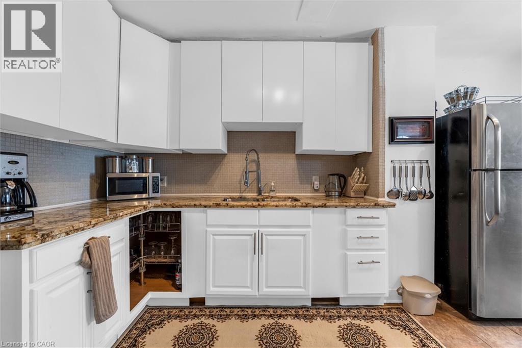 Kitchen with white cabinetry, appliances with stainless steel finishes, dark stone counters, and backsplash - 35 Bayfield Avenue, Hamilton, ON - Indoor Photo Showing Kitchen
